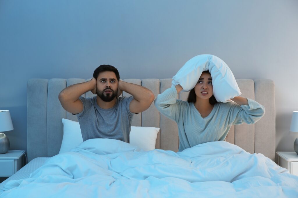 young,couple,suffering,from,noisy,neighbours,in,bed,at,home